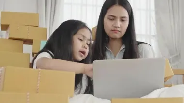 Asyalı kız ve kız kardeşler müşterilere gönderilmesi gereken ürünleri kontrol etmek için bir dizüstü bilgisayar kullanıyorlar. Evde, Sme, yeni iş konsepti.