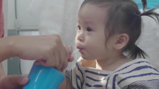 Een Aziatische Moeder Helpt Haar Dochter Uit Een Glas Drinken — Stockvideo