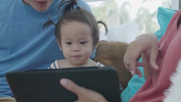 アジアの両親はタブレットコンピュータを使用しています 彼の娘を教えるのに役に立つ 自宅で慎重に利益を得るために技術を使用することで — ストック動画