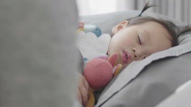 Küçük şirin bir Asyalı bebek mutlu bir şekilde uyuyor. Annesiyle yakından ilgilenirken Mutlulukla.