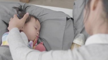 Küçük şirin bir Asyalı bebek mutlu bir şekilde uyuyor. Annesiyle yakından ilgilenirken Mutlulukla.