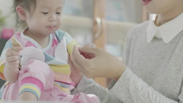 亚洲父母高高兴兴地在他自己家里的餐桌边给小女儿的午餐喂食 家庭欢乐时光 — 图库视频影像