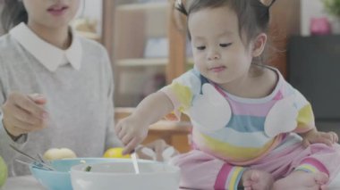 Asyalı ebeveynler kendi evindeki yemek masasında kızına yemek yediriyorlar. Aile mutlu anları.
