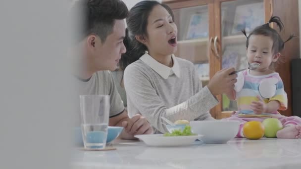 Азиатские Родители Кормят Маленькую Дочь Обедом Обеденным Столом Собственном Доме — стоковое видео