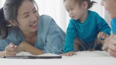 Asyalı ebeveynler tablet bilgisayar kullanıyorlar. Kızına bir şeyler öğretmek için. Teknolojiyi evde dikkatli bir şekilde yararlanmak için kullanarak..