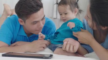 Asyalı ebeveynler tablet bilgisayar kullanıyorlar. Kızına bir şeyler öğretmek için. Teknolojiyi evde dikkatli bir şekilde yararlanmak için kullanarak..