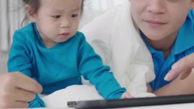 Asyalı ebeveynler tablet bilgisayar kullanıyorlar. Kızına bir şeyler öğretmek için. Teknolojiyi evde dikkatli bir şekilde yararlanmak için kullanarak..
