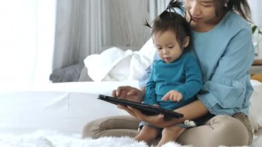 Asyalı ebeveynler tablet bilgisayar kullanıyorlar. Kızına bir şeyler öğretmek için. Teknolojiyi evde dikkatli bir şekilde yararlanmak için kullanarak..