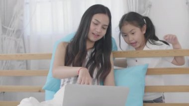 Asyalı kızlar ve kız kardeşler sanal dünyaya bağlanmak için dizüstü bilgisayarlar, bilgisayarlar ve tabletler kullanıyorlar. Küçük kız internet kullanarak evde dinlendi..