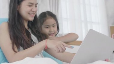 Asyalı kızlar ve kız kardeşler sanal dünyaya bağlanmak için dizüstü bilgisayarlar, bilgisayarlar ve tabletler kullanıyorlar. Küçük kız internet kullanarak evde dinlendi..