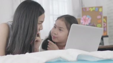 Asyalı kızlar ve kız kardeşler sanal dünyaya bağlanmak için dizüstü bilgisayarlar, bilgisayarlar ve tabletler kullanıyorlar. Küçük kız internet kullanarak evde dinlendi..