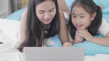 Asyalı kızlar ve kız kardeşler sanal dünyaya bağlanmak için dizüstü bilgisayarlar, bilgisayarlar ve tabletler kullanıyorlar. Küçük kız internet kullanarak evde dinlendi..