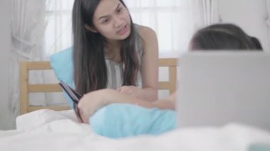 Asyalı kızlar ve kız kardeşler sanal dünyaya bağlanmak için dizüstü bilgisayarlar, bilgisayarlar ve tabletler kullanıyorlar. Küçük kız internet kullanarak evde dinlendi..
