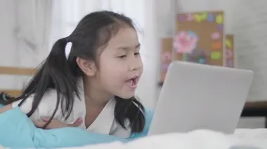 Asyalı kızlar siber dünyaya bağlanmak için dizüstü bilgisayar, tablet kullanıyorlar. Küçük kız internet kullanarak evde dinlendi..