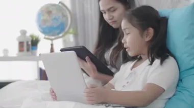 Asyalı kızlar ve kız kardeşler sanal dünyaya bağlanmak için dizüstü bilgisayarlar, bilgisayarlar ve tabletler kullanıyorlar. Küçük kız internet kullanarak evde dinlendi..