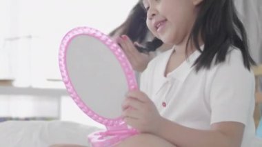 Sevgi dolu bir aile. İki kız kardeş saç yapıyor ve eğleniyorlar. Anne ve kızı makyaj yapıyor. Yatak odasındaki yatakta oturuyor..