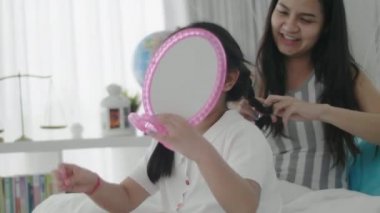 Sevgi dolu bir aile. İki kız kardeş saç yapıyor ve eğleniyorlar. Anne ve kızı makyaj yapıyor. Yatak odasındaki yatakta oturuyor..