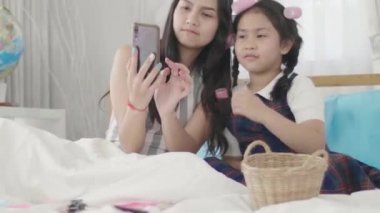 İki kardeş kız kardeş saç ve makyaj yapmayı bitirdikten sonra ikisi de kendi resimlerini çekmek için akıllı telefon kullandılar. Kendi evinde mutlu bir şekilde.