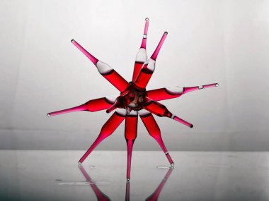 Cam bir laboratuvar rafında cam bir örümcek şeklinde birbirine yapıştırılmış kırmızı ilaç koronavirüs tedavisi ile cam ampuller.
