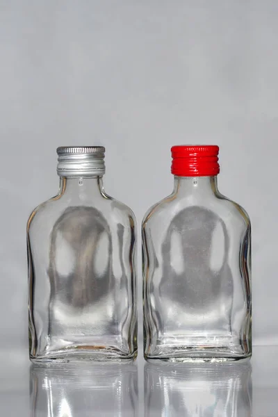 Zwei Leere Spirituosenglasflaschen Mit Weißen Und Roten Kappen Und Geisterschädeln — Stockfoto