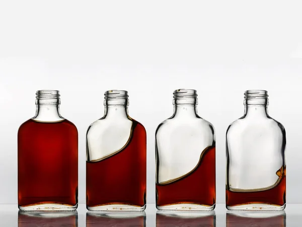 Четыре Стеклянные Бутылки Подряд Разным Количеством Коричневого Цвета Напитков Каждом — стоковое фото