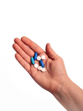 Beyaz bir arka planda ilaç ve tabletlerle izole edilmiş bir kadın eli.