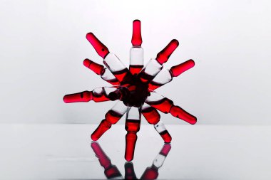 Cam bir laboratuvar rafında örümcek şeklinde yapıştırılmış kırmızı ilaç vitamini olan cam ampuller.
