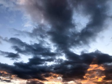 Gökyüzünde kara bulutlar ve gün batımında dramatik bir hava.