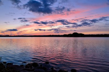 Gün batımında gölün manzarası. Renklerle, siluetlerle ve huzurlu bir atmosferle.