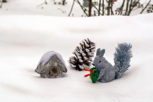 Inverno na composição florestal. Esquilo decorativo com um saco de presentes, casa-colisão e oco — Fotografia de Stock