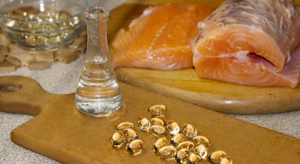 Balık yağı sıvı ve kapsül somon üzerinden. Kırmızı somon taze bir ahşap kesme tahtası üzerinde balık. Yağı omega 3 ve omega 6.