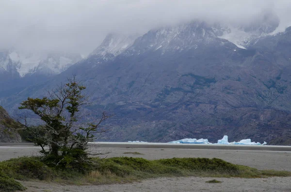灰色湖上的冰山和乌云覆盖的群山. — 图库照片