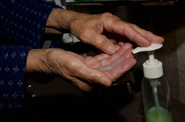 Mulher mais velha lavando as mãos para evitar o coronavírus — Fotografia de Stock