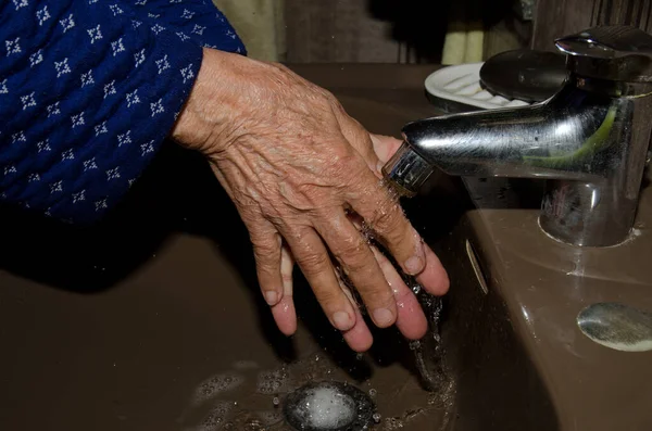 Oudere vrouw wast haar handen om coronavirus te voorkomen — Stockfoto