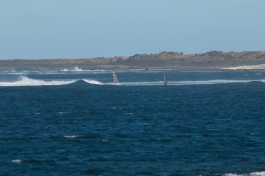 Majanicho sahilinde dalgalarda sörf yapan rüzgar sörfçüleri.