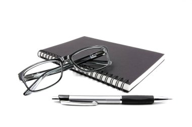 Defter gözlük ve beyaz zemin üzerine kalem.