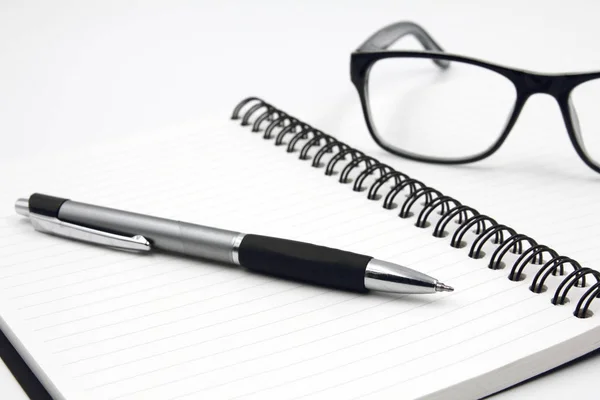 Notebook okulary i pióra na białym tle. — Zdjęcie stockowe