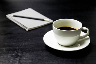 Defter ve kalem üzerinde tahta arka plan ile kahve.