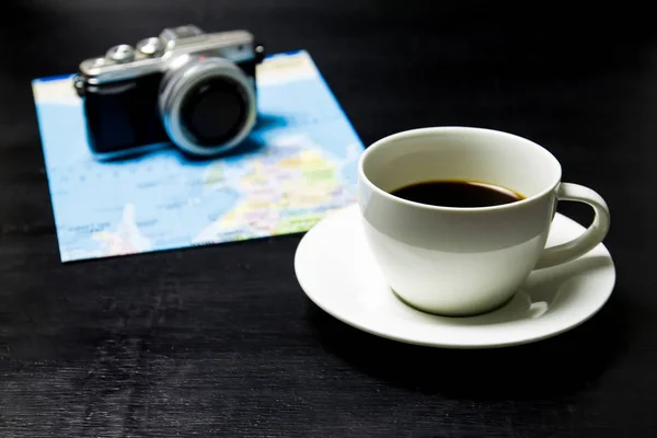 Coffee with camera and world map on wood background.