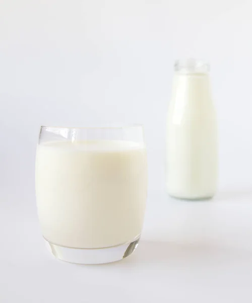Μπουκάλι γάλα και ποτήρι γάλα σε λευκό φόντο — Φωτογραφία Αρχείου