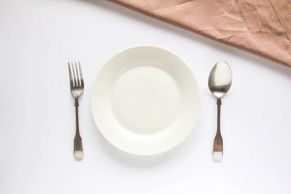 Ein weißer Teller mit silberner Gabel und Löffel — Stockfoto