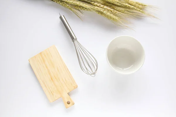Tábua de corte de madeira, batedor e tigela branca sobre fundo branco — Fotografia de Stock