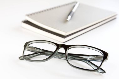 Gözlük, defter ve kalem beyaz arka plan üzerinde.