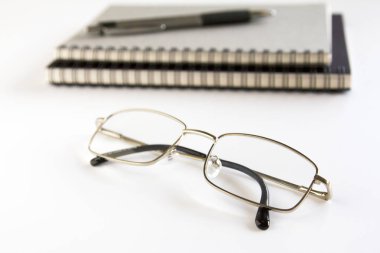 Gözlük, defter ve kalem beyaz arka plan üzerinde.