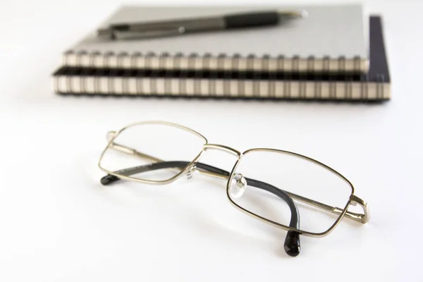 Lunettes, cahier et stylo sur fond blanc . — Photo