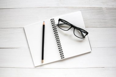 Beyaz ahşap masa üzerinde iş amaçlı aksesuarları: defter, kalem, gl