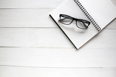 Defter ve Beyaz ahşap masa arka plan üzerinde gözlük.