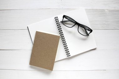 Defter ve Beyaz ahşap masa arka plan üzerinde gözlük.