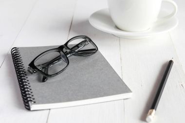 Beyaz ahşap masa üzerinde iş amaçlı aksesuarları: defter, kalem, gl