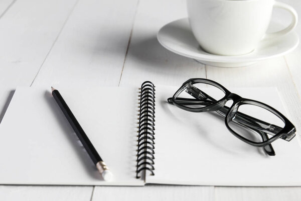Business accessories on white wooden table : notebook,pencil, gl